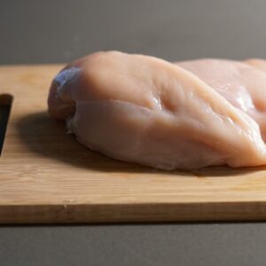 a piece of raw chicken on a cutting board